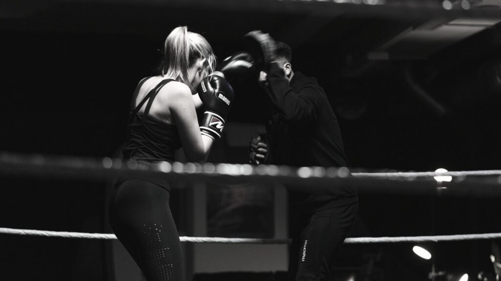 man holding boxing pads for girl punching