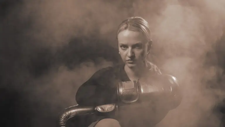 Girl posing having boxing gloves in hand smoke in background